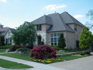 brick house with grass, flowers and flowering shrub