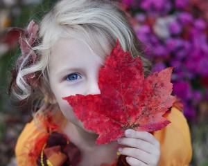 girl holding red fall maple leaf