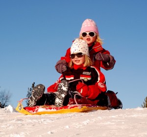 two girls sledding outside 