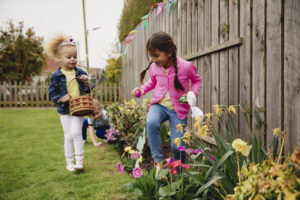 Two little girls searching for easter eggs in a backyard 