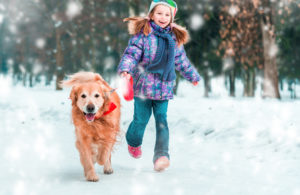 little girl and dog running through the snow 